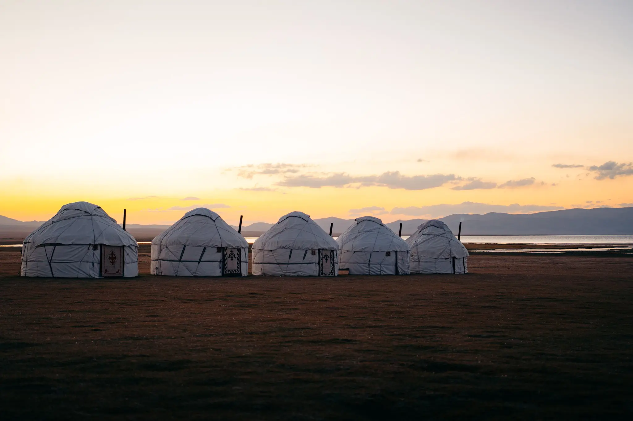 row of yurts at sunset by a lake in Kyrgyzstan