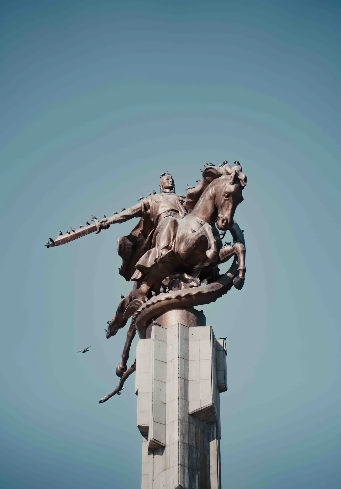 Reiterstatue mit Vögeln vor blauem Himmel