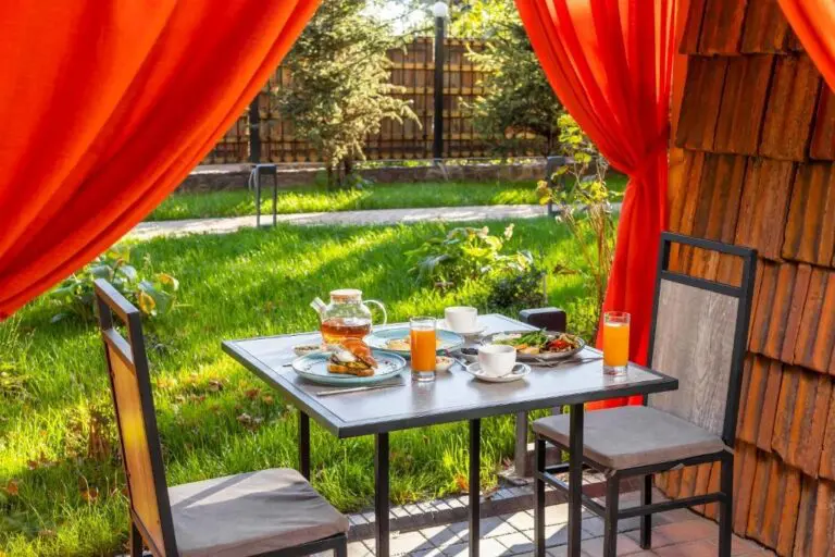 outdoor breakfast table with tea, juice, and food in a garden