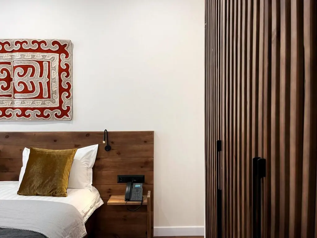 hotel room interior with wooden headboard and patterned tapestry