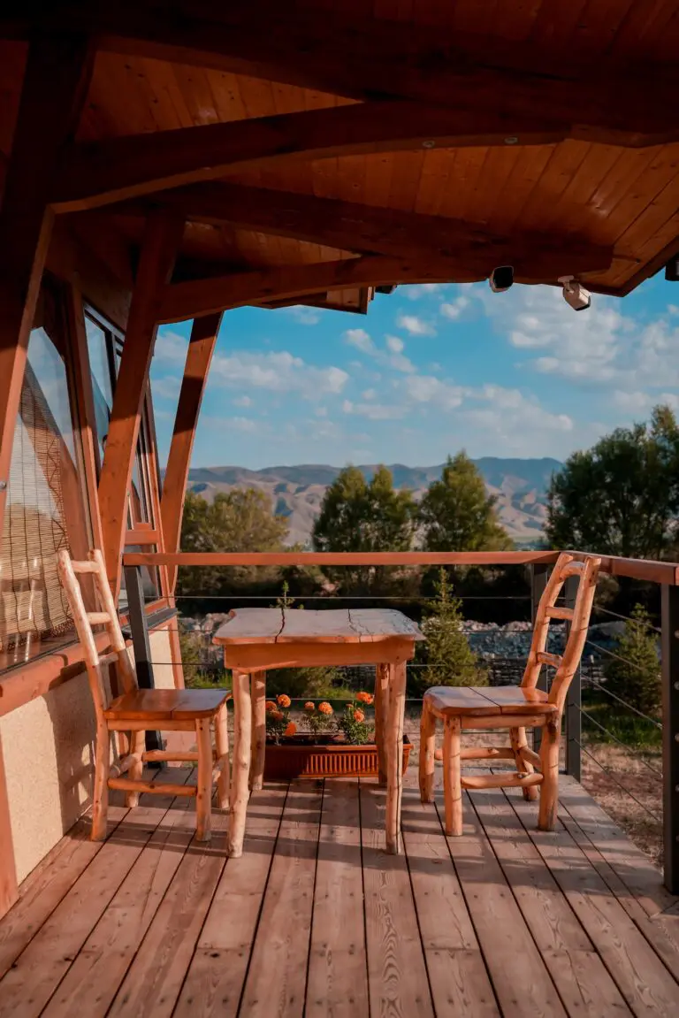 wooden table and chairs on a balcony with mountain views