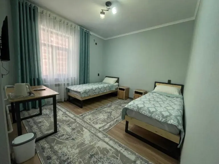 Twin bedroom in a guesthouse with teal curtains and patterned rugs