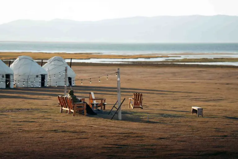 person relaxing by yurts and lake in Kyrgyzstan