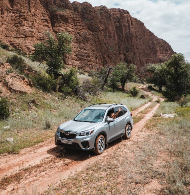 silver SUV driving on dirt road in Kyrgyzstan mountains