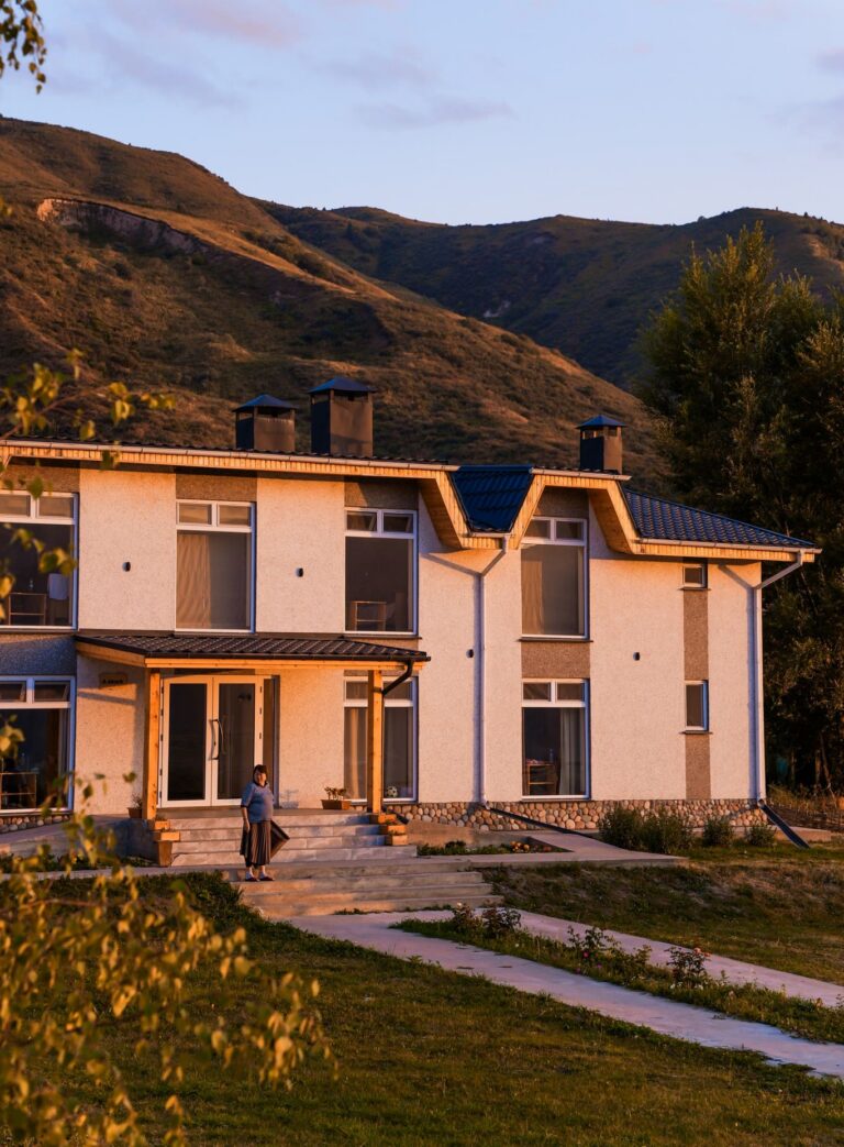 woman standing outside a large house in Kyrgyzstan mountains at sunset